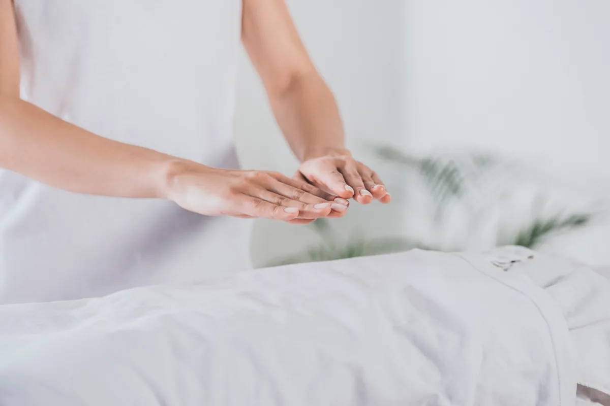 Hands held above a covered body during a Reiki session